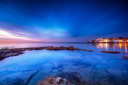 Coastal city on sunset, view on Batroun and mediterranean sea, glowing lights from the houses at...
