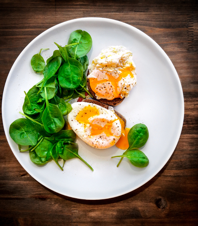 Delicious poached eggs on the big white plate on the wooden table, beautiful tasty food still life, traditional breackfast, healthy organic nutritionの写真素材
