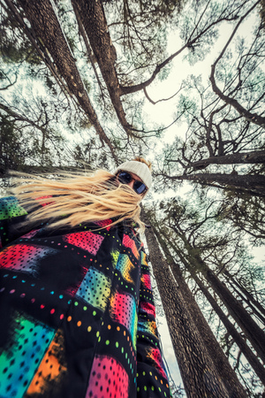 Perspective photo of a teen girl standing in the forest among giant Cedar trees, spending time outdoors in the nature, bottom view の写真素材