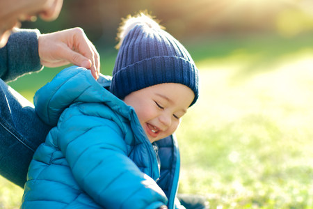 Cute little boy with his father playing outdoors on the fresh green grass field in bright sunny day, happy family with pleasure spending time together, enjoying first spring dayの写真素材