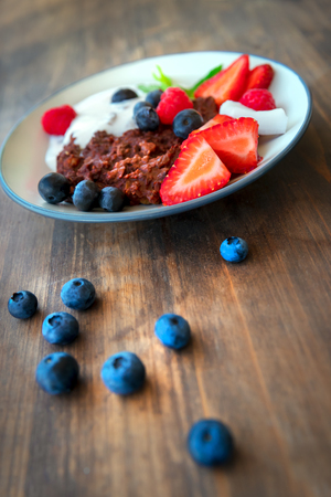 Tasty healthy breakfast, organic food still life on brown wooden table background, granola with fruits and yogurt for healthy nutrition, delicious vegetarian mealの写真素材