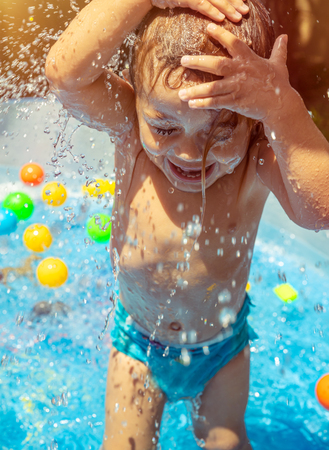 Happy child in the pool, cheerful little baby boy having fun, splashing water, enjoying summer holidays on a beach resortの写真素材