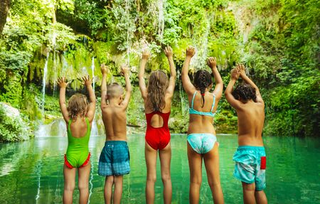 Happy children jumping into the mountain's lake, amazing nature, great greenery surrounded the lake, holidays in the beautiful natural place, summer campの写真素材