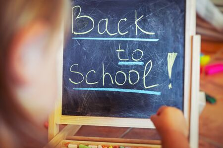Little boy preparing for school, sweet adorable child writing words on the chalkboard in his playroom at home, back to school conceptの写真素材