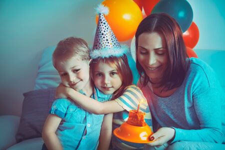 Happy family celebrating birthday, little boy with mom congratulating his sister with birthday,...