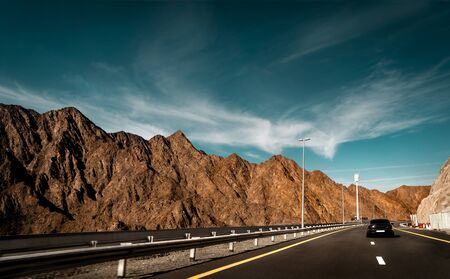 Road trip, car on the highway along beautiful mountains, vacation in Fujeira, UAE
