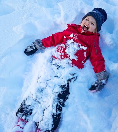 Little girl playing snow angel, cheerful child lying down in the snow and screaming of joy, outdoor fun, enjoying winter holidays, happy carefree childhood
の写真素材