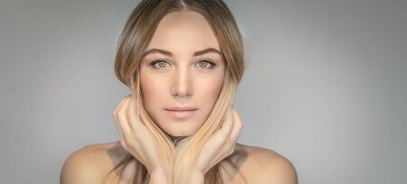 Authentic portrait of a beautiful blond woman isolated on gray background, genuine beauty of a young adult female, natural makeup and fashion look, photo with copy space, panoramic photo formatの写真素材