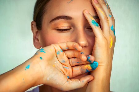 Beautiful woman with a dreamy face and paint-stained fingersの写真素材