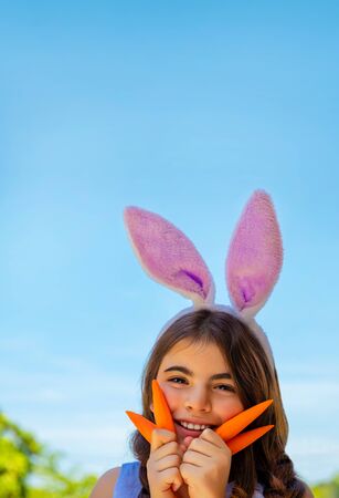 Portrait of a cute little bunny girl with carrots enjoying Easterの写真素材