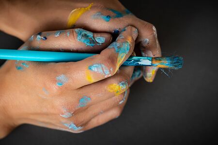 Close Up photo of a paint-stained painters hands holding paintbrushの写真素材