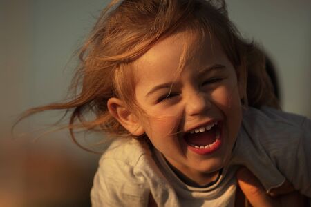 Portrait of a nice cheerful boy laughing, with pleasure spending time outdoors, having fun playing games, happy carefree childhoodの写真素材