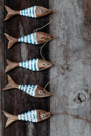 Stylish Wooden Decoration for Beach House. Wooden Table with Five Little Wooden Fishes on it. Fishing Background. Accessories of Fisherman's Hut.の写真素材