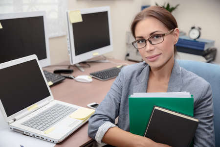 Portrait of a nice office worker, pretty female with folders in hands at work, successful business...