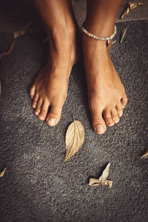 Welcome Fall Background. Closeup Concept Photo of a Barefoot Women Feet and Dry Leaves. Autumn Season Theme.の写真素材