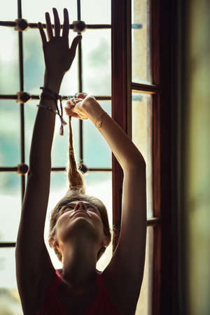 Portrait of a Gorgeous Woman With Raised up Hands near the Window. Gentle Female Dancing at Home.
