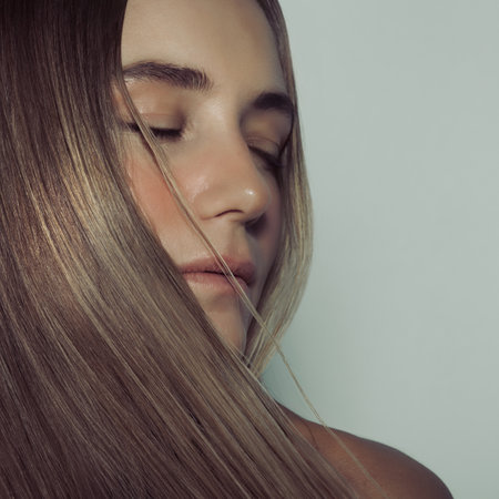 Fashion Portrait of a Beautiful Female with Natural Long Straight Hair and Perfect Skin Isolated on Clear Background. Keratin Hair Straightening Treatment. Hair and Skin Careの写真素材
