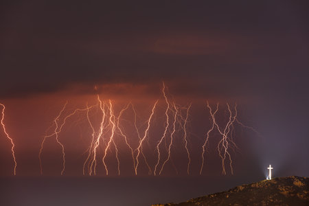 Amazing Landscape of a Beautiful Zippers in Dark Night Sky. Illuminated Cross Standing on top of the...