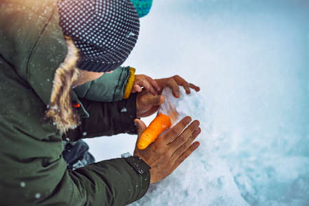 Father and Little Son Building a Snowman in the Snowy Park. Put a carrot instead of nose. Traditional Wintertime Joy. Happy Christmas Holidays.の写真素材