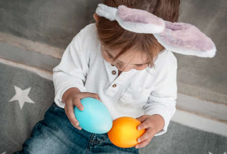 Cute Little Baby Dressed as Festive Bunny Playing with Colorful Decorative Eggs.の写真素材