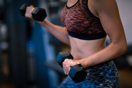 Girl with Dumbbells is Engaged in the Gym. Reduces Weight.