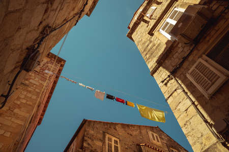Croatia. Sunny Day in Dubrovnik. The Clothes Drying out on the Rope. Typical Balkan Street. Perspective View on Old Historical Buildings.の写真素材