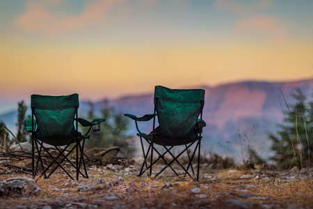 Two Empty Camping Chairs Standing on the Top of the Mount. Perfect Place for Watching Sunset. Actice Relaxation Lifestyleの写真素材