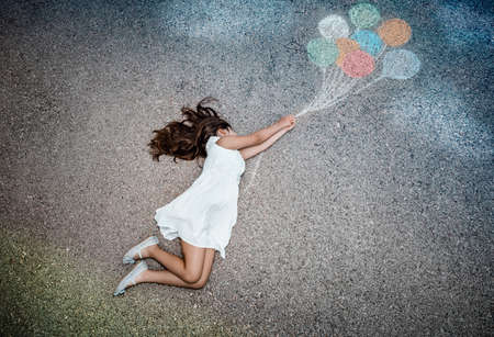 Conceptual Image of Freedom Joy and Happiness. Little Girl Flying Away on Colorful Balloons. Enjoying Life. Dreamy Childhood. Creative Imagination.の写真素材