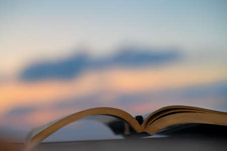 Spend a Nice Evening Reading an Interesting Book Outdoors in Mild Sunset Light. Keep a Pen to Mark the Most Important Things. Calm Pleasant Pastime.の写真素材