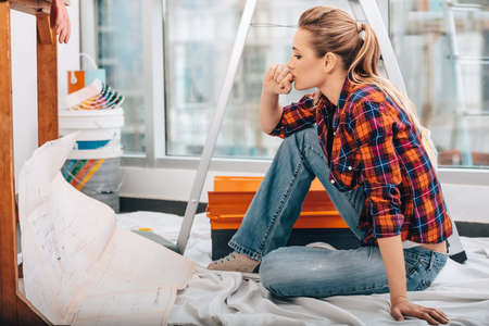 Portrait of a Beautiful Serious Engineer Woman Thinking about Apartment Construction Plan. House Renovation.の写真素材