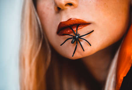 Halloween Makeover Fashion Ideas. Beautiful Female Face with Spiders. Holiday Makeup. Bright Red Lipstick. Blond Hair. Girl Model. Lips Closeup.の写真素材