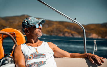 Portrait of a Handsome Man Relaxing on the Sailboat. Enjoying Bright Warm Sunny Day in Luxury Water...