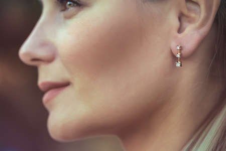 Closeup Portrait of a Beautiful Young Woman Wearing Gorgeous Stylish Earring. Profile Portrait. Luxury Fashionable Jewelry.の写真素材