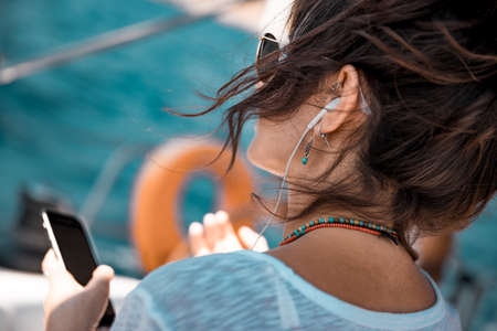 Traveler Girl with Pleasure Listening Music on the Sailboat. Enjoying Nice Melody. Luxury Summer...