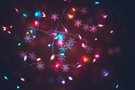 Beautiful Glowing Christmas Background. Cute Little Snowflakes on Dark Backdrop Decorated with Colorful Festoon. Happy New Year Background.の写真素材