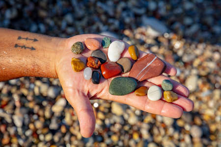 Conceptual Photo of a Summer Mood. Male Hand with Little Colorful Pebbles on the Palm. Crystals...