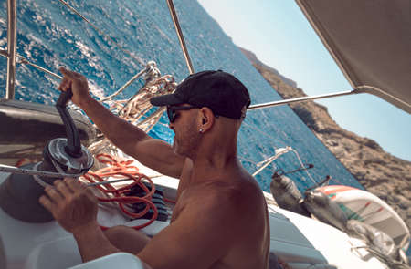 Handsome Sailor Working on Sailboat. Enjoying Travel along the Sea. Yachting Sport. Summer Holidays.の写真素材