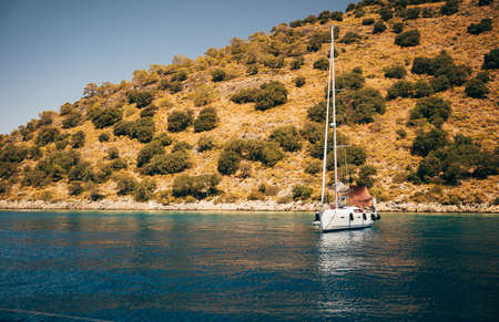 Beautiful Seascape over Mountains Background. Sailboat Floating in the Water. Active Vacation. Peaceful Landscape. Nice Summer Trip along Turkey.の写真素材