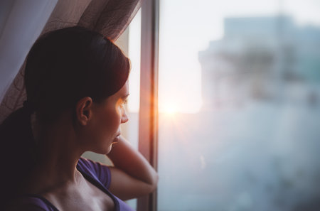 Mindfulness concept. Authentic Portrait of a Nice Woman Looking at the Sunset Light. Domestic life. People at Homeの写真素材