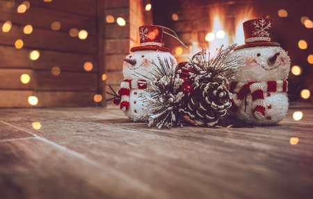 Christmas Home Decor. Winter House Decorated with Festoon. Two Little Snowman and Pine Tree Branch Near Fireplace. Photo with Copy Space.の写真素材
