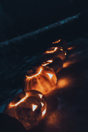 Glowing Halloween Pumpkins Placed on a Mysterious Dark Pathway at Nightの写真素材