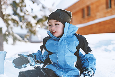 Baby plays with a snow on a sunny dayの写真素材