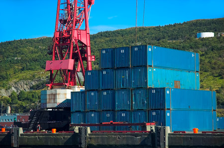 Blue shipping containers beside red crane