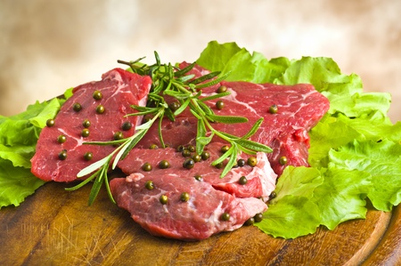 Row Steak whit green pepper and rosemary on plate of woodの写真素材
