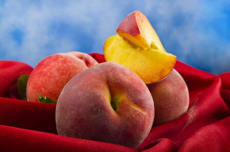 fresh peach fruits with cut on red velvetの写真素材