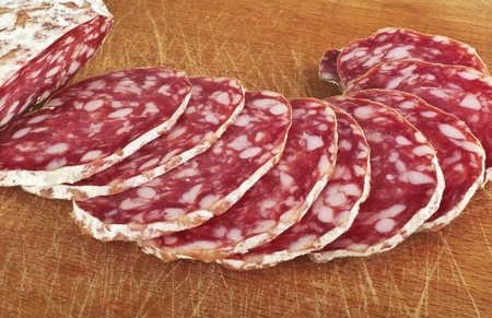Salami with slices on woodの写真素材