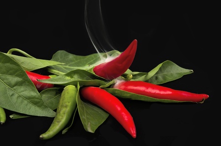 Red chili peppers with a flame on blackの写真素材