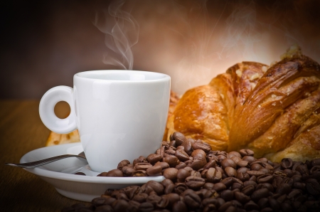 Coffee smoking on the coffee beans and croissant backgroundの写真素材
