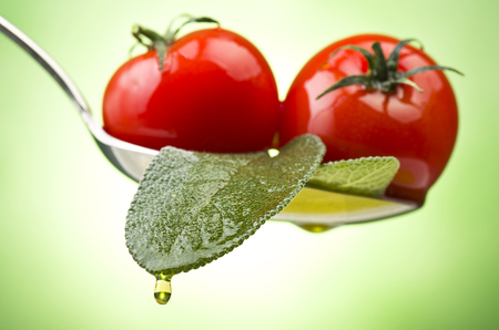  Spoon with little tomatoes and oil on a green background の写真素材