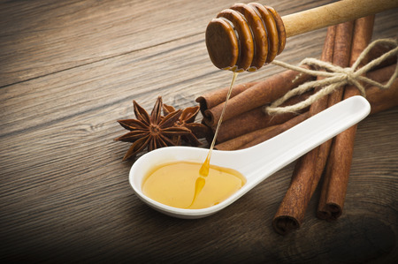 wooden honey dipper and spices on wood tableの写真素材